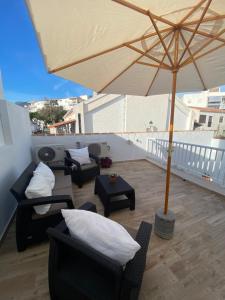 a patio with chairs and an umbrella on a balcony at CASA NOAH in Nerja