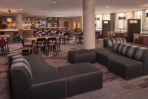 a lobby with couches and tables and a restaurant at Courtyard Fort Meade BWI Business District in Annapolis Junction