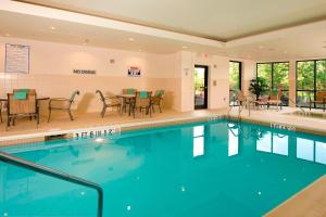 a swimming pool with tables and chairs in a hotel at Courtyard by Marriott Atlanta Buford Mall of Georgia in Buford