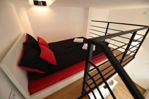 a loft bed with red and black pillows on it at BEL GALLERIES ( Karadjordjeva street ) in Sajmište