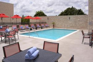 a swimming pool with tables and chairs and umbrellas at Courtyard by Marriott Austin Pflugerville in Pflugerville