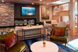 Fairfield Inn & Suites by Marriott Columbus, IN في كولومبوس: لوبي فيه كراسي وطاولات وتلفزيون