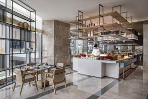 a chef in a kitchen with a table and chairs at Courtyard by Marriott Chengdu South in Chengdu