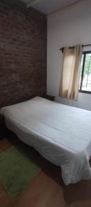 a white bed in a room with a window at Casa en colonia para 7 personas in Colonia del Sacramento