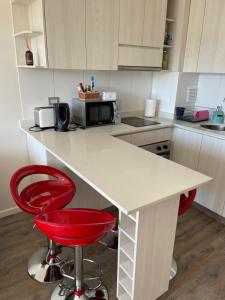 cocina con encimera blanca y 2 taburetes rojos en Departamento nuevo en exclusivo sector de Puerto Montt, en Puerto Montt