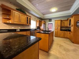 a large kitchen with wooden cabinets and black counter tops at Hidden Gem Exuma - KING BED master suite and central air in Georgetown