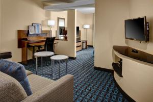 a hotel room with a couch and a table and a television at Fairfield Inn and Suites by Marriott Atlanta Suwanee in Suwanee