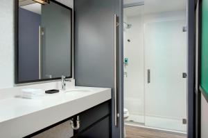 a bathroom with a sink and a mirror and a shower at Aloft Florence in Florence