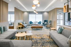 un vestíbulo con sofás, mesas y sillas en TownePlace Suites by Marriott Oconomowoc, en Oconomowoc