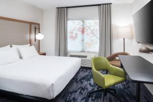 ポート・ウェントワースにあるFairfield Inn & Suites by Marriott Savannah I-95 Northのベッド、デスク、椅子が備わるホテルルームです。