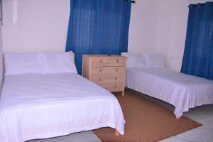 two beds in a bedroom with blue curtains and a dresser at Villa Caleta Pool & Heated Jacuzzi in La Romana