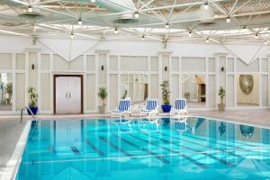 a pool with blue water and blue chairs in a building at Sheraton Riyadh Hotel & Towers in Riyadh