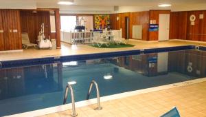 a large swimming pool with blue water in a building at Colonial Inn Ellsworth in Ellsworth