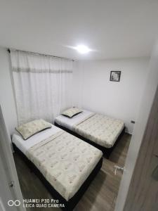 2 bedden in een kamer met een raam bij Hermoso Apartamento en Circasia, Quindío. in Circasia