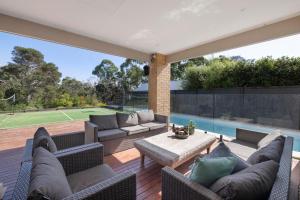 un patio con sofá, mesa y piscina en Corymbia Mount Martha, en Mount Martha