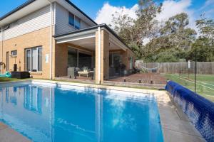 a swimming pool in front of a house at Corymbia Mount Martha in Mount Martha