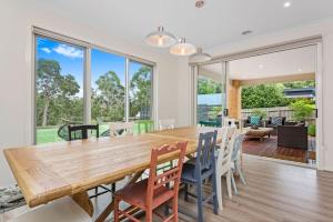 Un comedor con una gran mesa y sillas de madera. en Corymbia Mount Martha, en Mount Martha