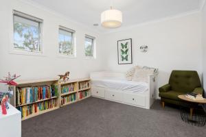 a bedroom with a bed and a chair and bookshelves at Corymbia Mount Martha in Mount Martha