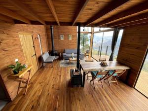 Pokój z drewnianą podłogą, stołem i krzesłami w obiekcie Entre Cumbres - Cabaña con vista a la cordillera 