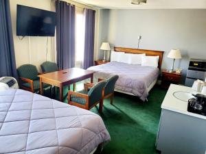 Monte Vista的住宿－Monte Villa Hotel，酒店客房带两张床和一张桌子以及椅子。
