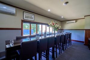 - une longue table dans une pièce avec des chaises et des fleurs dans l'établissement Yandina Hotel, à Yandina