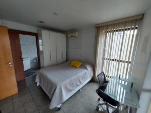 a bedroom with a bed and a desk and a window at Loft Espaçoso e Aconchegante in Niterói