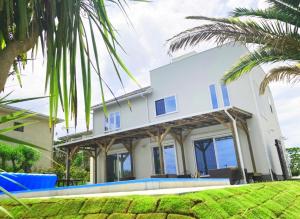 a white house with blue windows and a palm tree at HOKULANI by the sea - Vacation STAY 68088v in Isumi