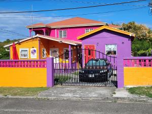 a colorful house with a fence in front of it at Tequila Sunrise Antigua in Osbourn