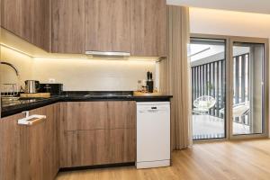 a kitchen with wooden cabinets and a white dishwasher at Marinha Grande Apartamentos N2 ZEN in Marinha Grande