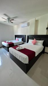 two beds in a bedroom with a ceiling at Hotel Real Jaguar in Tuxtla Gutiérrez