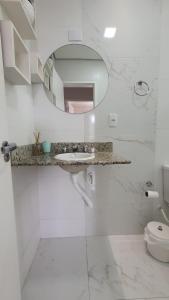 Baño blanco con lavabo y espejo en Ótimo apto de temporada em BC, en Balneário Camboriú