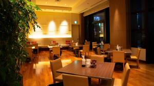 富山市にあるオークスカナルパークホテル富山の木製のテーブルと椅子、大きな植物のあるレストラン
