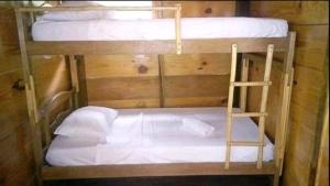 two bunk beds with white sheets and a ladder at Cabaña Altos de San Carlos in Santa Marta