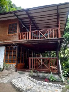 a large wooden house with a porch and a balcony at Cabaña Altos de San Carlos in Santa Marta