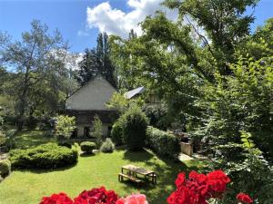 un jardín con flores rojas y una casa en Gîte Souvigny-de-Touraine, 3 pièces, 6 personnes - FR-1-381-457, en Souvigny-de-Touraine