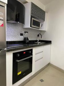 a kitchen with a black oven and a microwave at Elegante apartamento en Playa el Angel in Porlamar