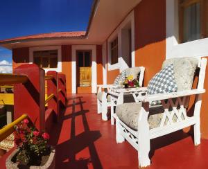 Amantani Pachatata Lodge في Ocosuyo: شرفة مع الكراسي والورود على المنزل