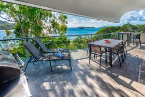 einen Balkon mit einem Tisch, Stühlen und Meerblick in der Unterkunft Waves 6 on Hamilton Island by HIHA in Hamilton Island