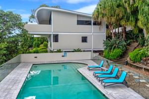 a house with a swimming pool and two blue chairs at Waves 6 on Hamilton Island by HIHA in Hamilton Island