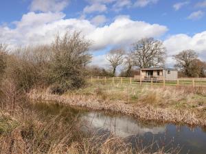 a small shack in a field next to a river at The Swift in Whitchurch