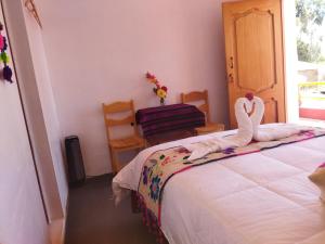 Un dormitorio con una cama con dos cisnes. en Amantani Pachatata Lodge en Ocosuyo