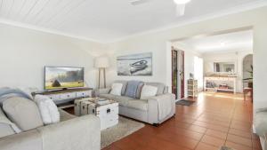 a living room with two couches and a tv at Sea Cottage - Beachside Paradise in Beachmere