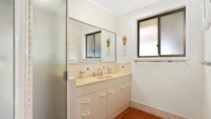 a white bathroom with a sink and a mirror at Sea Cottage - Beachside Paradise in Beachmere +6 photos
