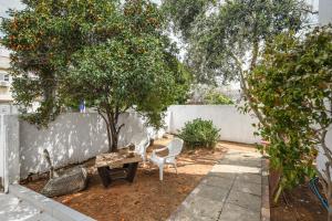 um jardim com duas cadeiras, uma mesa e uma laranjeira em Chic 2BR Apt w Garden in Ramat Hasharon by Sea N' Rent em Ramat Hash Sharon