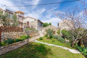a house with a stone wall and a yard at House Marija in Mošćenička Draga