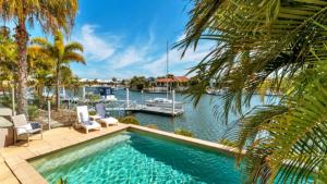 a swimming pool with a boat in the water at Spacious Canal Home With Pool in Banksia Beach