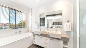 a bathroom with two sinks and a tub and a mirror at Spacious Canal Home With Pool in Banksia Beach