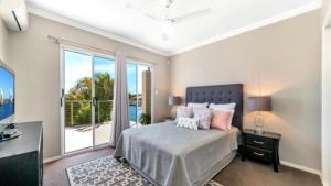 a bedroom with a bed and a large window at Spacious Canal Home With Pool in Banksia Beach