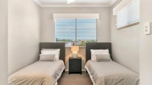 two beds in a room with a window at Spacious Canal Home With Pool in Banksia Beach