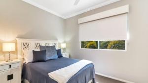 a bedroom with a blue bed and a window at Spacious Canal Home With Pool in Banksia Beach